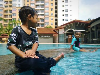 Full length of boys sitting in swimming pool