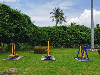 Empty park bench on field against sky
