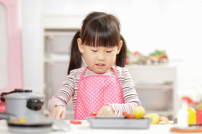 Young girl pretend play food preparing at home