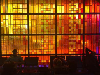 Rear view of man sitting in illuminated room