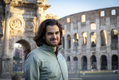 Happy moment in rome. young smiling man posing for a photo in front of the colosseum.