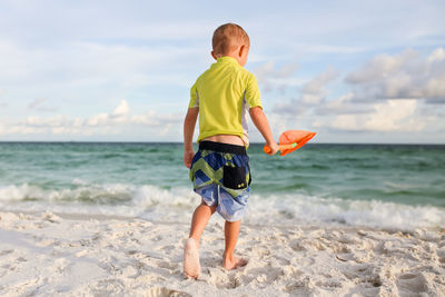 Rear view of boy walking at beach