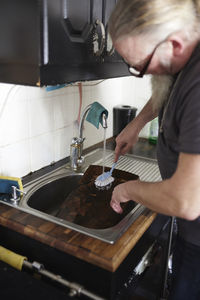 Man in kitchen washing dishes at kitchen sink