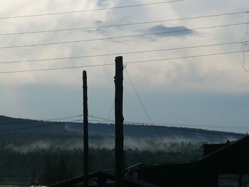 Low angle view of silhouette electricity pylon against sky