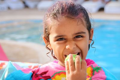 Portrait of cute girl eating food by swimming pool