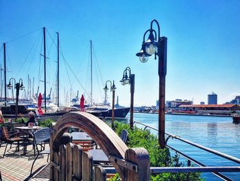 Boats moored at harbor against blue sky