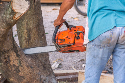 Midsection of man holding orange while standing on wood