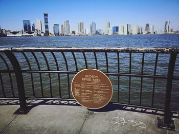 Text on railing by sea against buildings in city