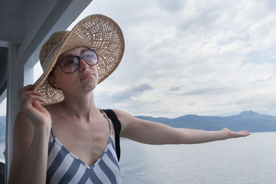 Midsection of woman wearing hat against sea against sky