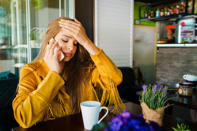 Frustrated young woman using mobile phone while sitting in cafe