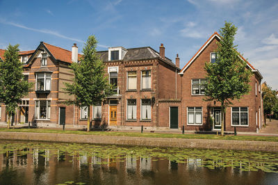 Canal with streets on the banks and brick houses in weesp. a pleasant small village in netherlands.