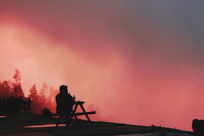 Silhouette man walking against orange sky