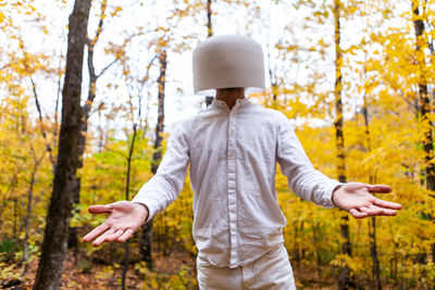 Midsection of man standing by tree in forest during autumn