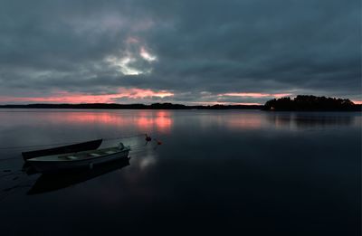 Boats moored in lake against sky during sunset