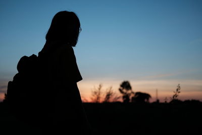 Silhouette woman standing on field against sky during sunset
