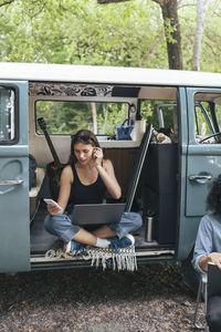 Young woman using smart phone while male friend sitting by during vacation