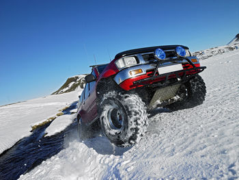 Red suv crossing river in the winter on the icelandic highlands