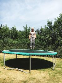 Woman levitating over trampoline against plants