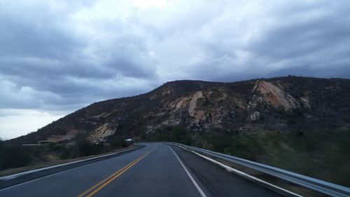 Country road against cloudy sky