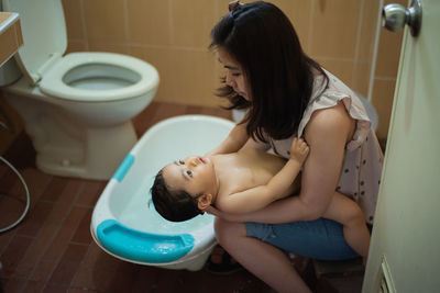 Young woman sitting in bathroom at home