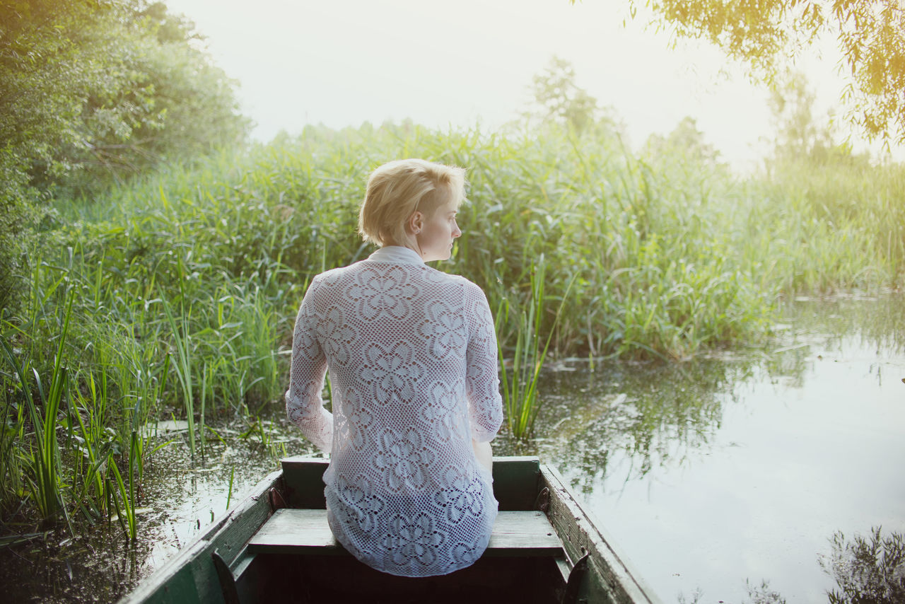 REAR VIEW OF WOMAN STANDING AGAINST LAKE