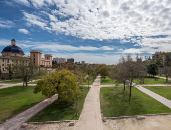 Footpath amidst trees and buildings against sky