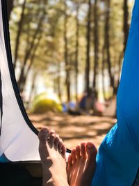 Low section of woman relaxing in tent at forest