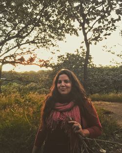 Portrait of smiling young woman standing by tree