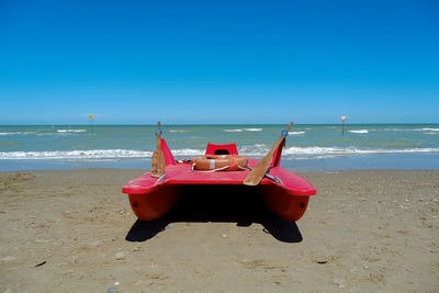 Deck chairs on beach against clear blue sky