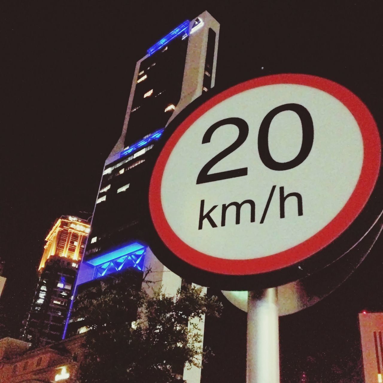 building exterior, low angle view, architecture, built structure, text, illuminated, communication, western script, night, city, road sign, guidance, information sign, sign, lighting equipment, building, street light, sky, outdoors, clear sky