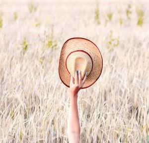 Midsection of person holding plant on field