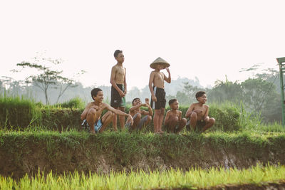 People sitting on field against clear sky