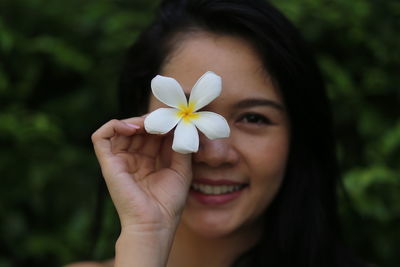 Close-up portrait of smiling woman holding flowering plant