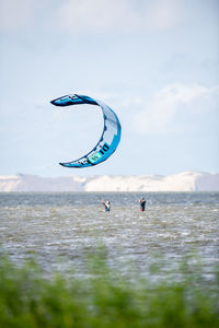People paragliding in sea against sky