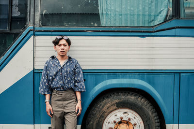 Portrait of man standing against blue wall