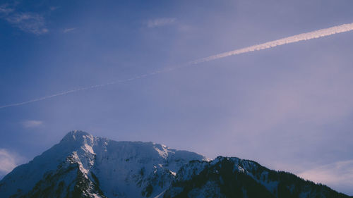 Low angle view of snowcapped mountains against blue sky