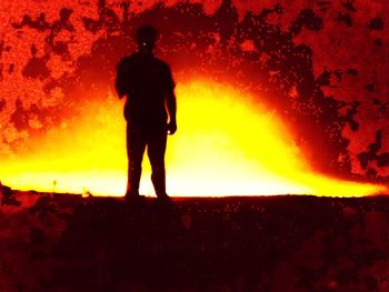 Rear view of silhouette man standing against orange sky