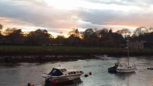 Boats moored in lake against sky during sunset