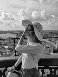 Side view of woman standing in balcony against cityscape