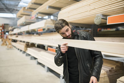 Male customer examining wooden plank in hardware store
