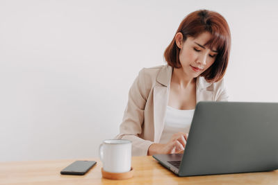 Young woman using mobile phone while sitting on table