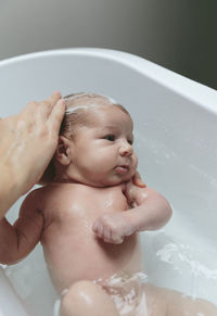 Cropped hands of mother bathing son in bathtub at bathroom