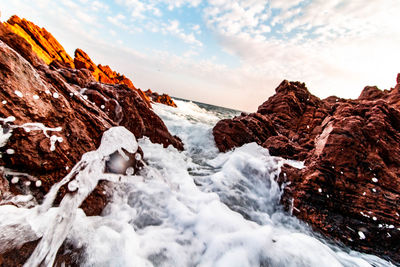 Scenic view of rocks in sea against sky during winter