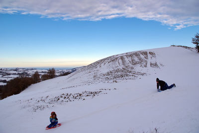 People on snowcapped mountain against sky