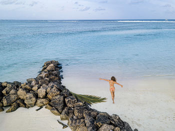 Woman with arms outstretched enjoying vacation beach, maldives