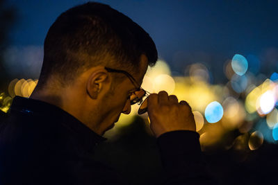 Close-up portrait of young man holding illuminated light at night