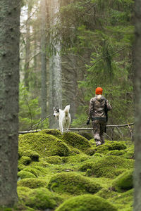 Rear view of man with dog in forest