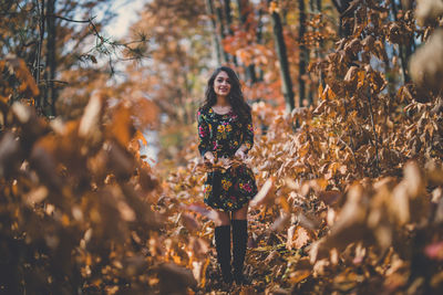 Portrait of young woman standing by tree