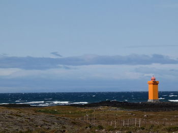 Lighthouse by sea against sky