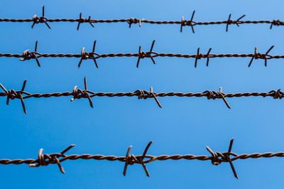 Low angle view of barbed wire against blue sky